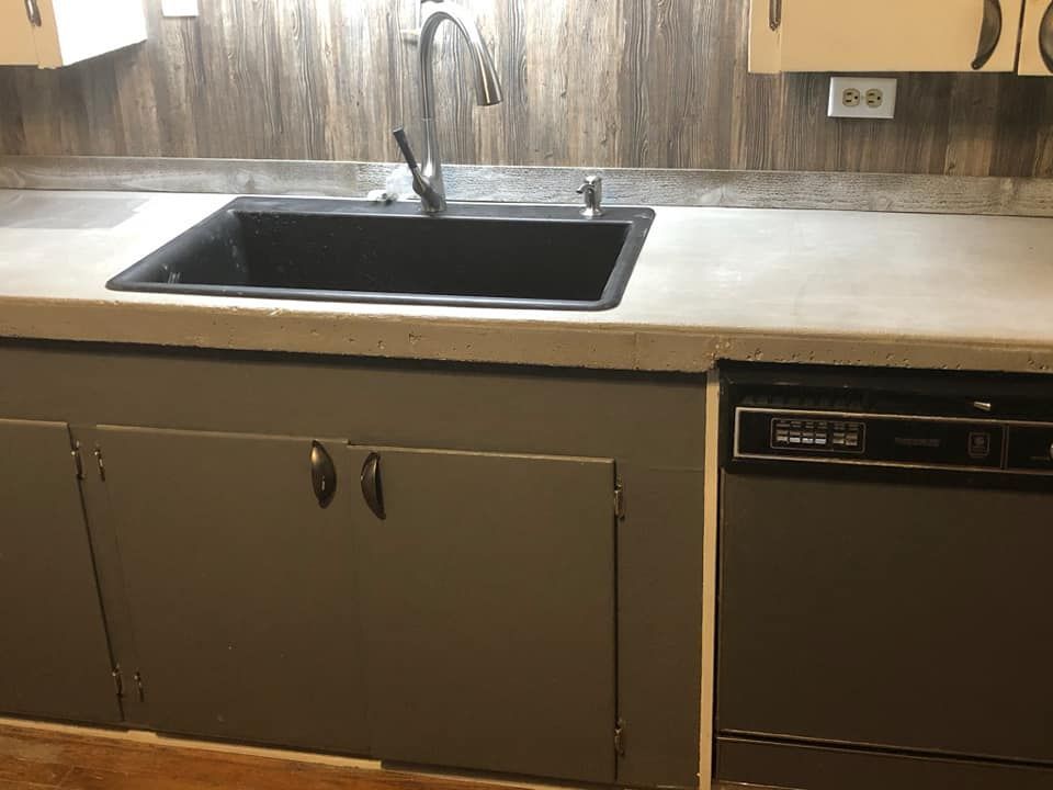 A kitchen with a sink , dishwasher , and cabinets.