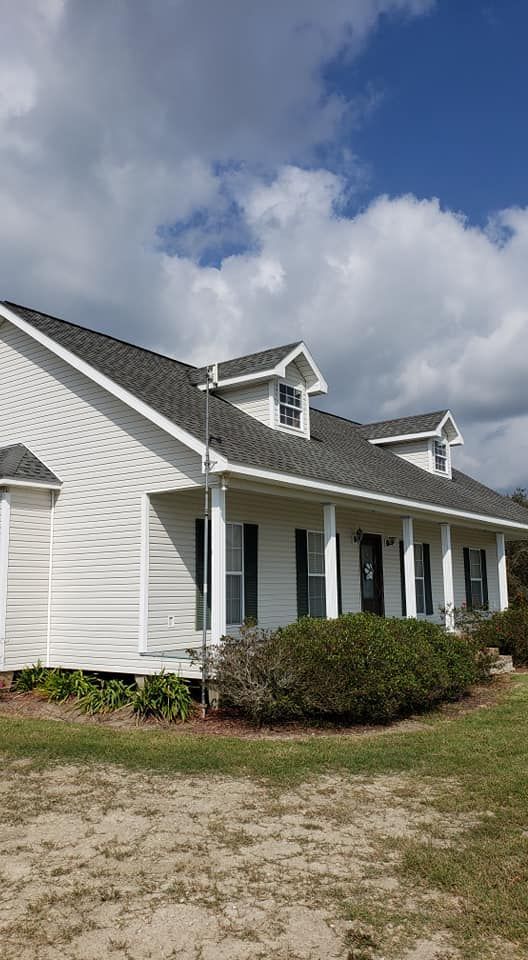 A white house with a porch and a gray roof