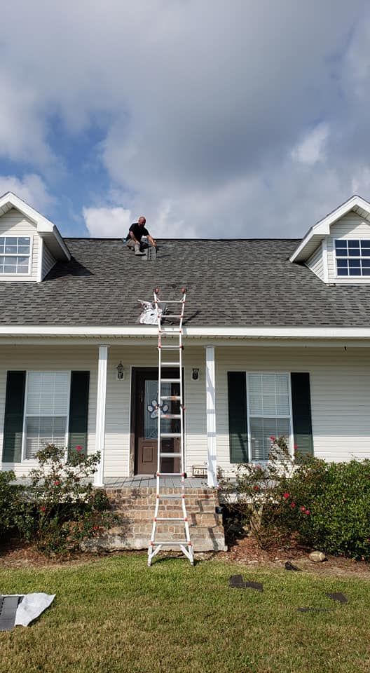 A man is standing on a ladder on the roof of a house.