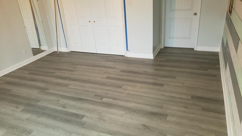 An empty room with a wooden floor and a mirror.