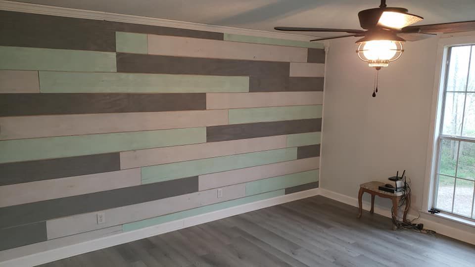 A living room with a wooden wall and a ceiling fan.