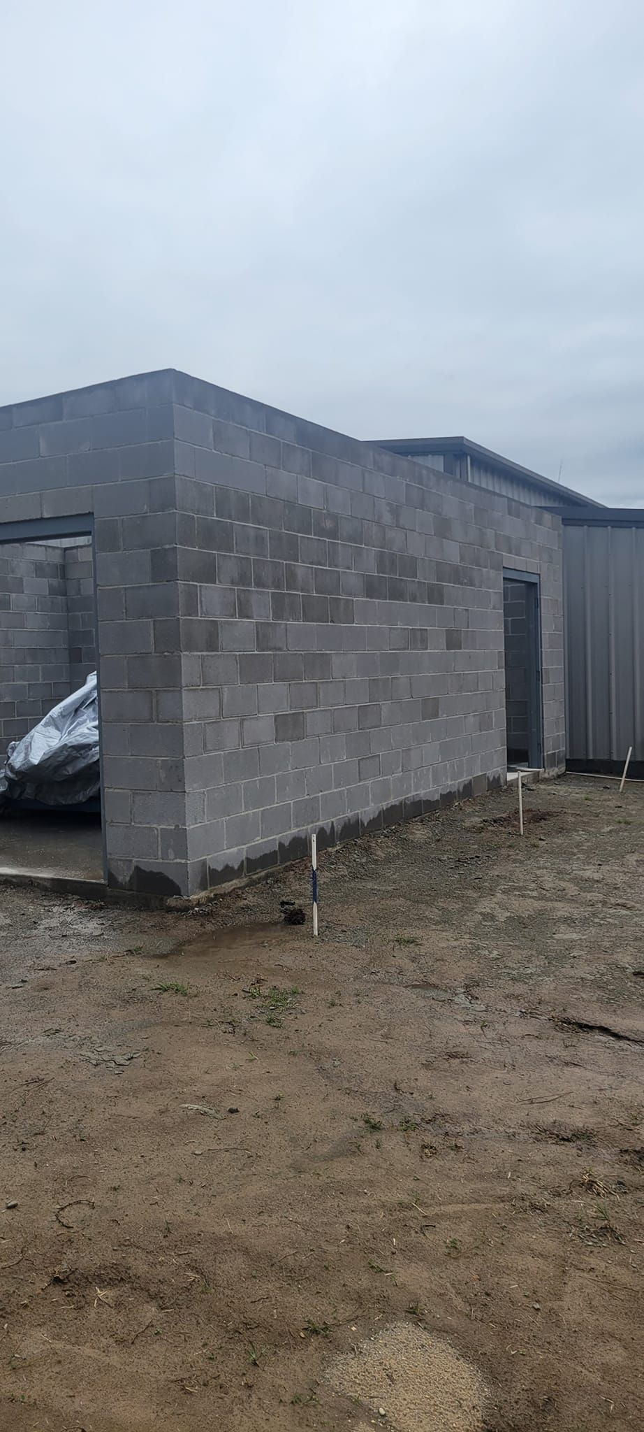 A car is parked in front of a building under construction.