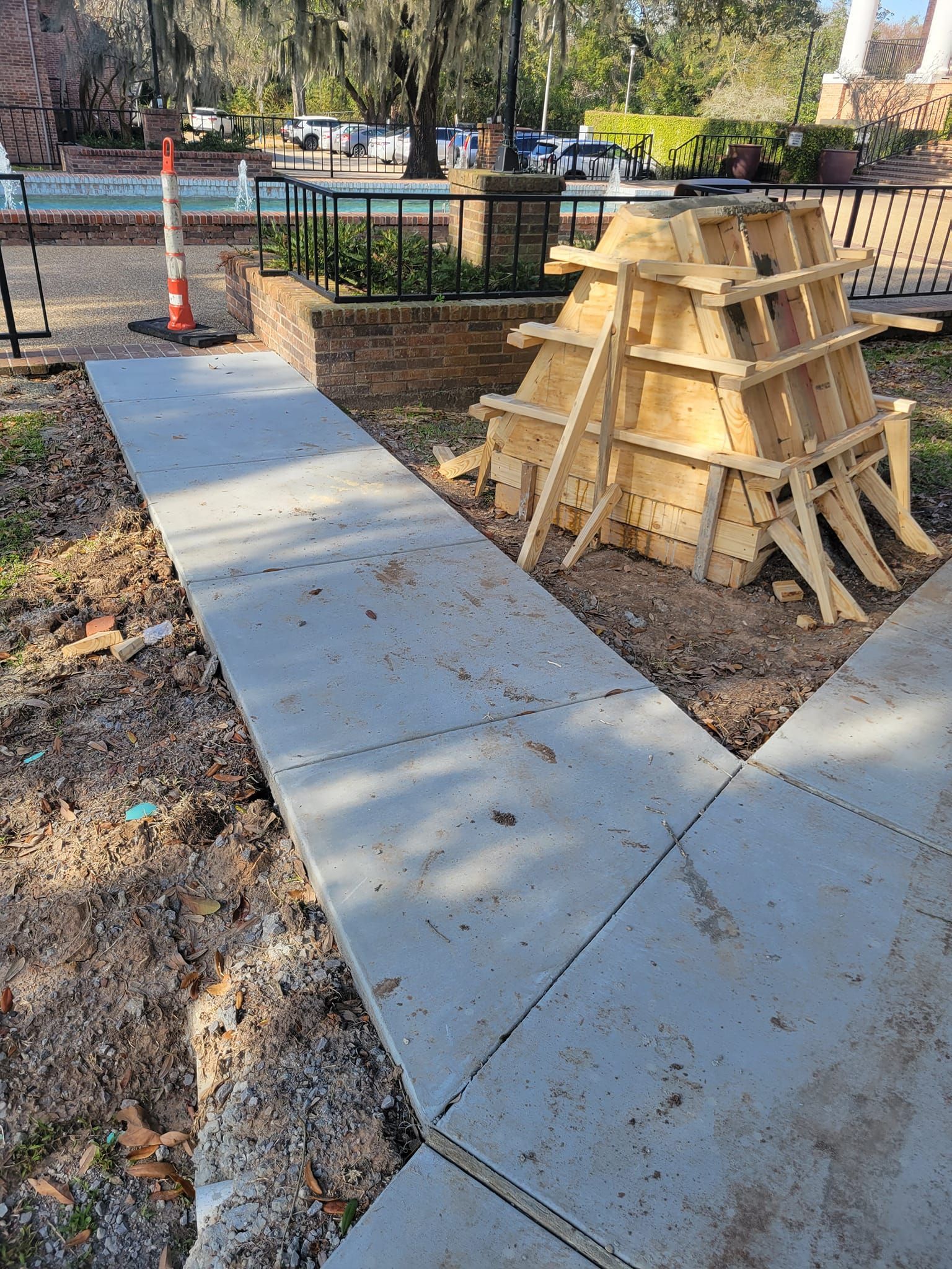 A concrete walkway is being built next to a pile of wood.