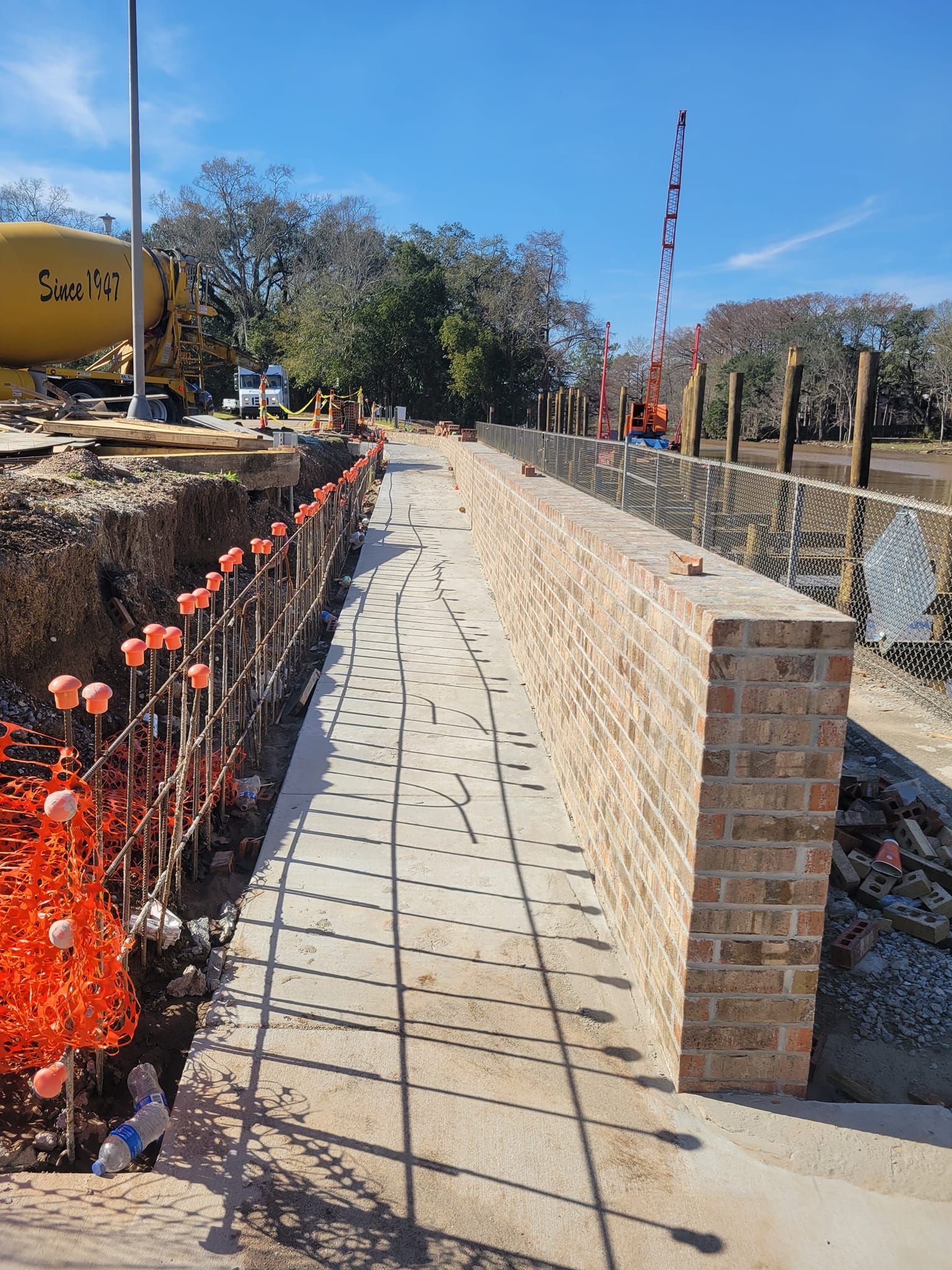 A brick wall is being built next to a concrete walkway.