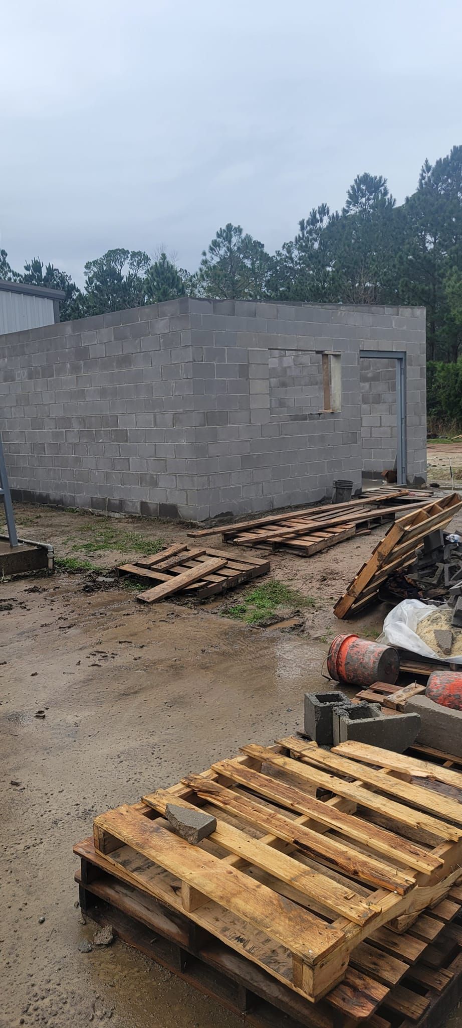 A pile of wooden pallets is sitting in front of a building under construction.