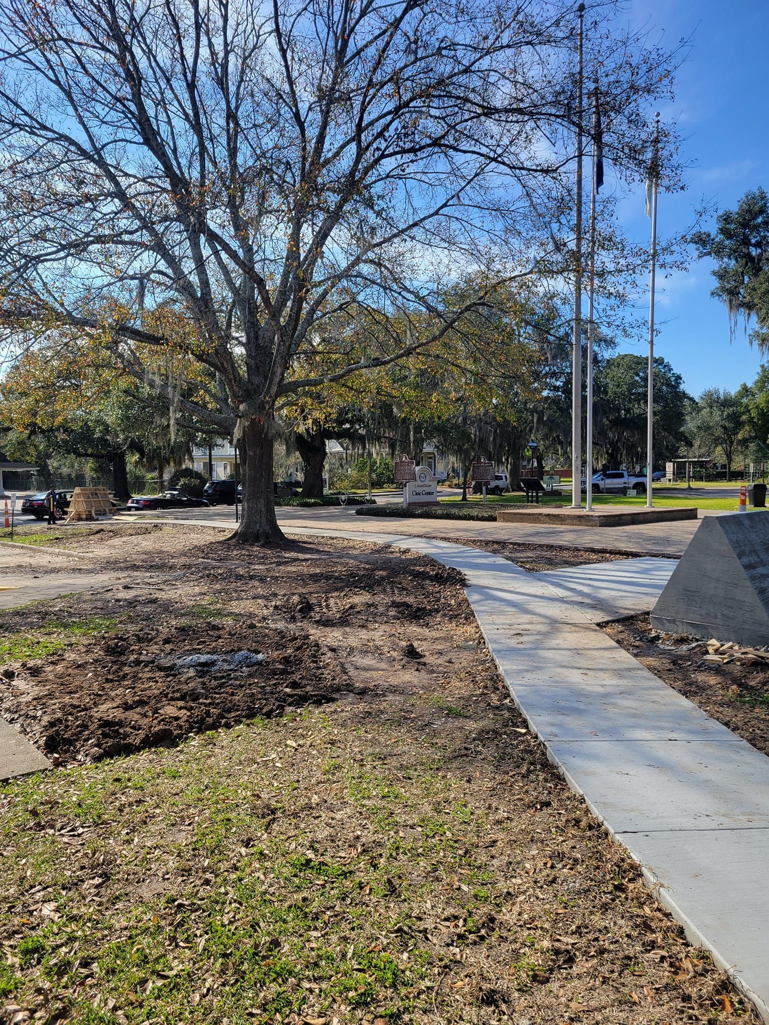 A concrete walkway leading to a park with trees and grass.