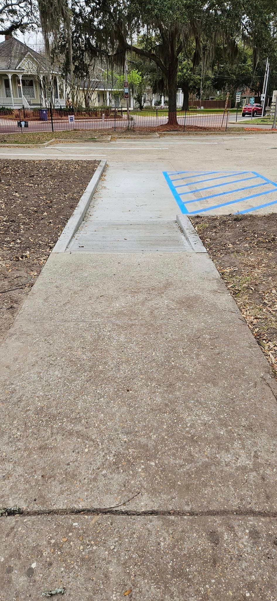 A concrete walkway leading to a handicapped parking spot.