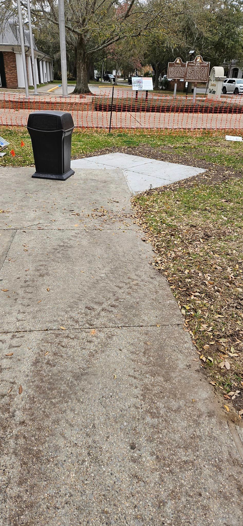 A trash can is sitting on the sidewalk next to a fire hydrant.