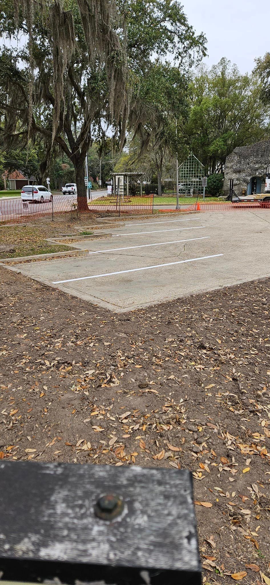 A parking lot with a lot of leaves on the ground and trees in the background.