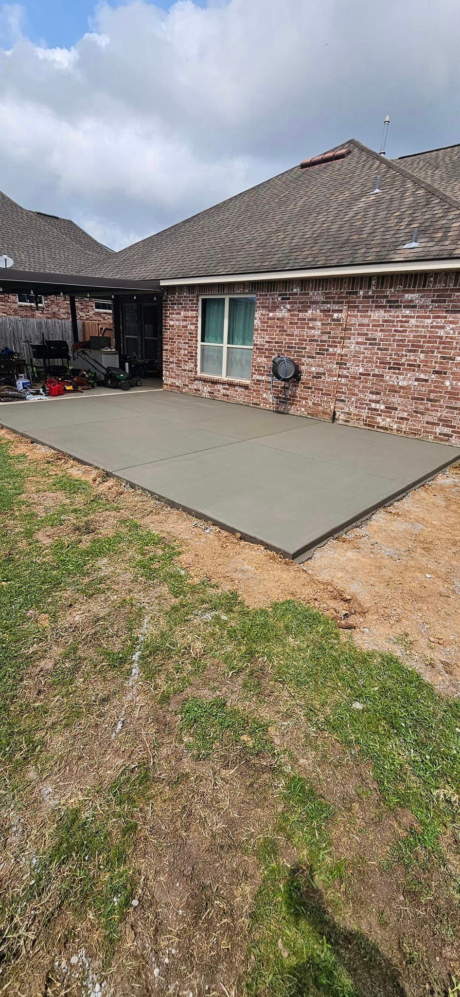 A concrete patio is being built in front of a brick house.