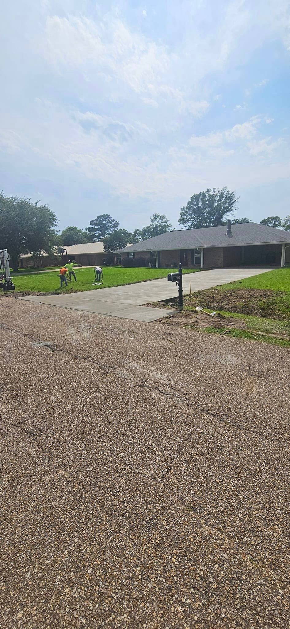 A gravel driveway leading to a house with a tractor in the background.
