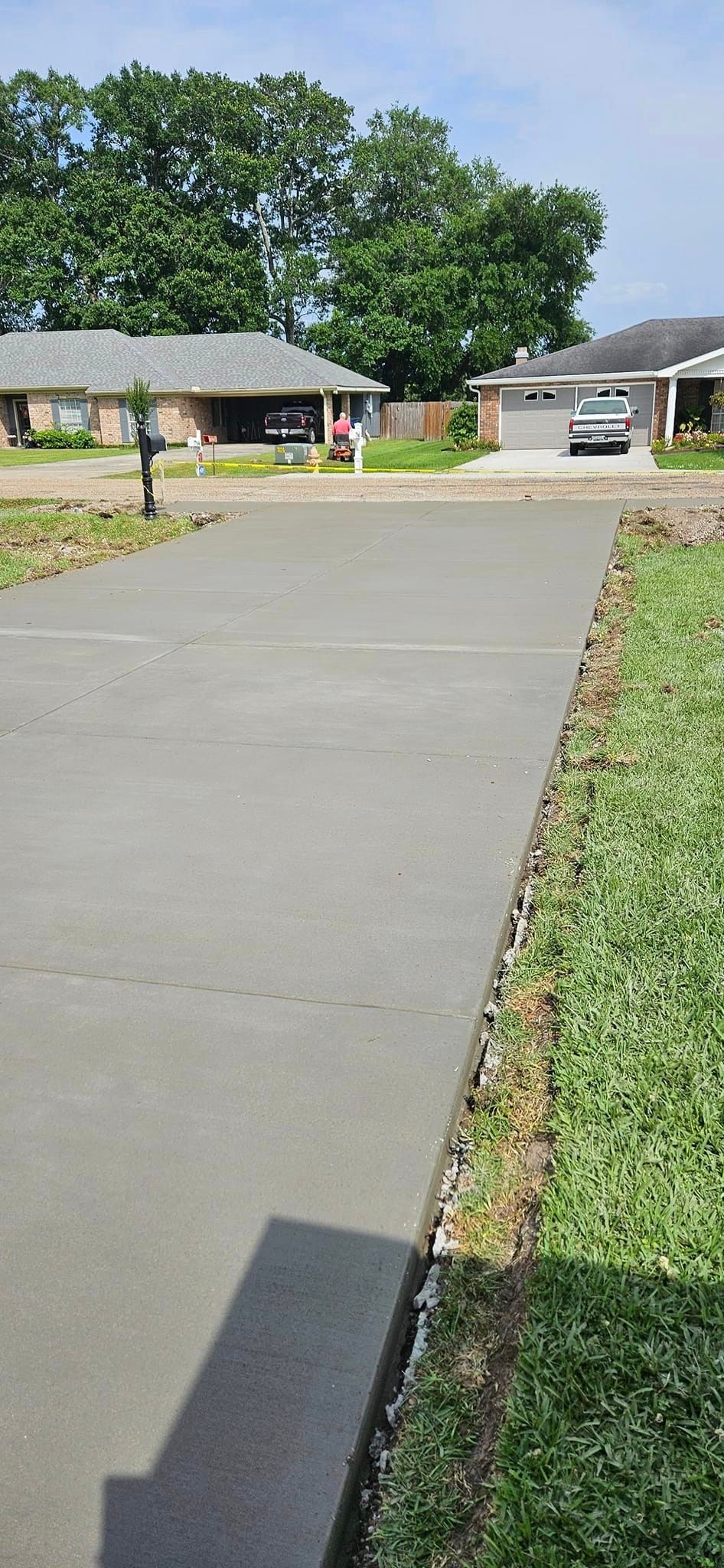 A concrete driveway leading to a house in a residential neighborhood.