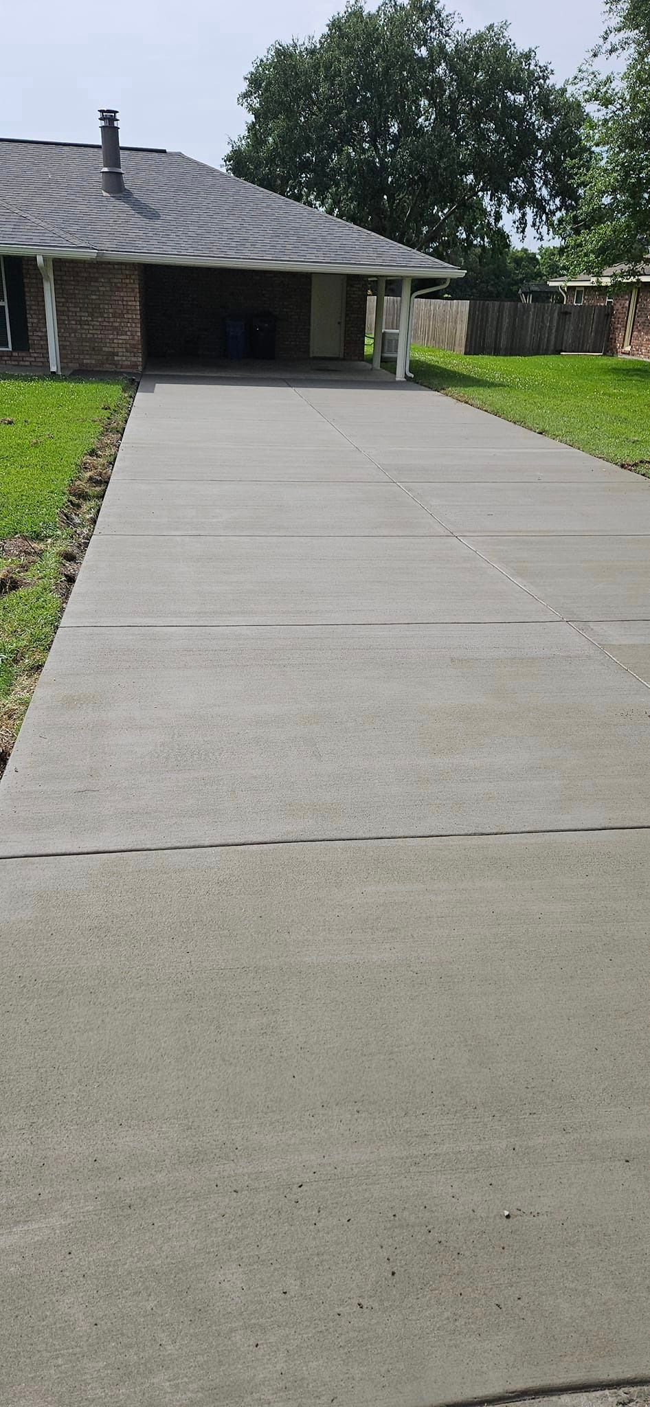 A long concrete driveway leading to a house.