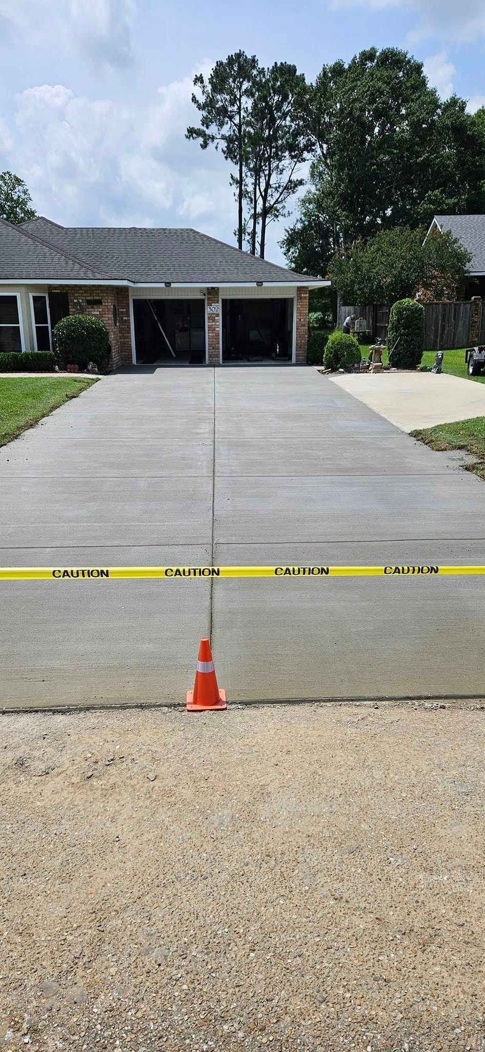 A concrete driveway leading to a house with a yellow tape around it.