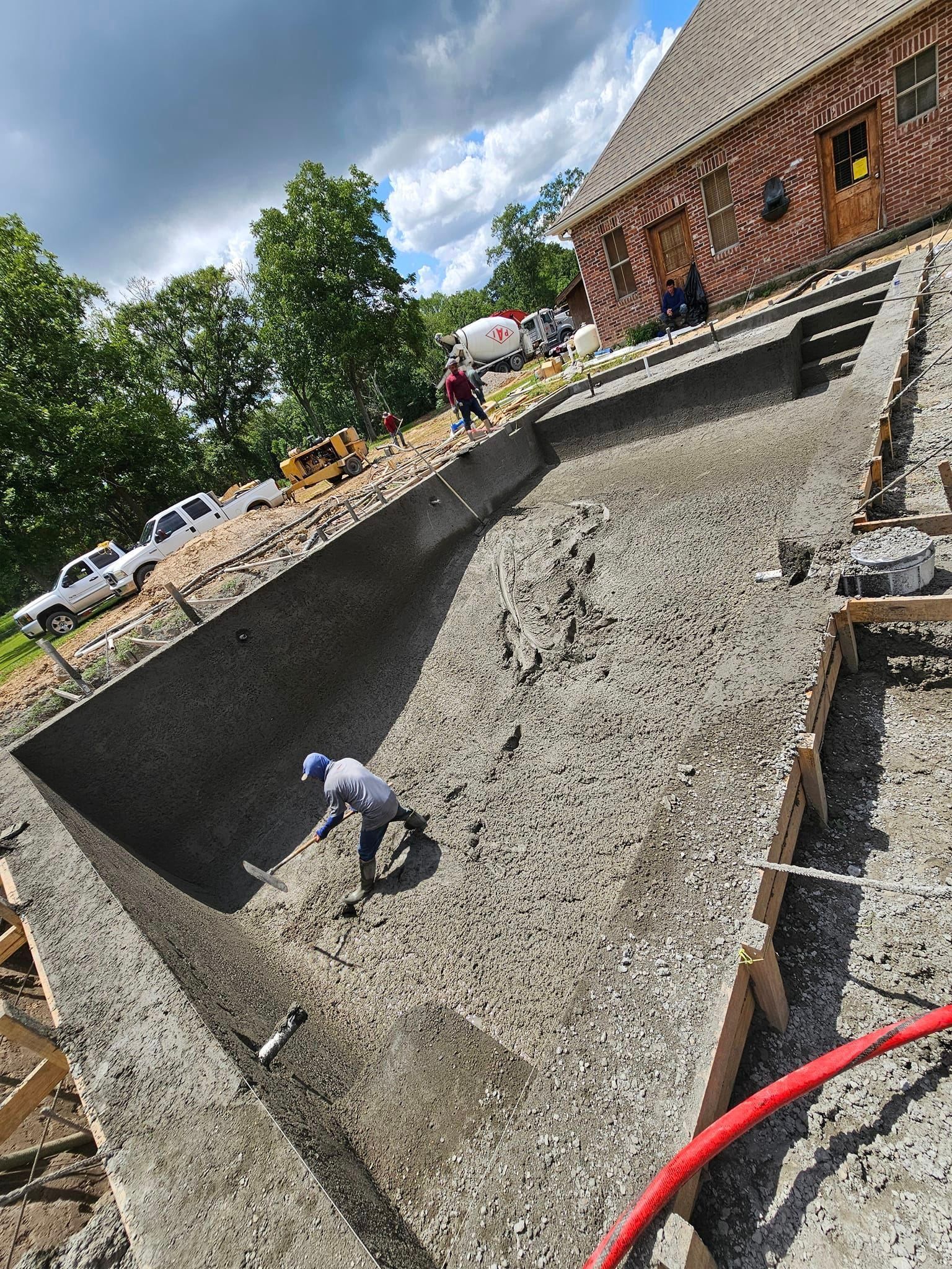 A man is digging a hole in the ground next to a swimming pool.