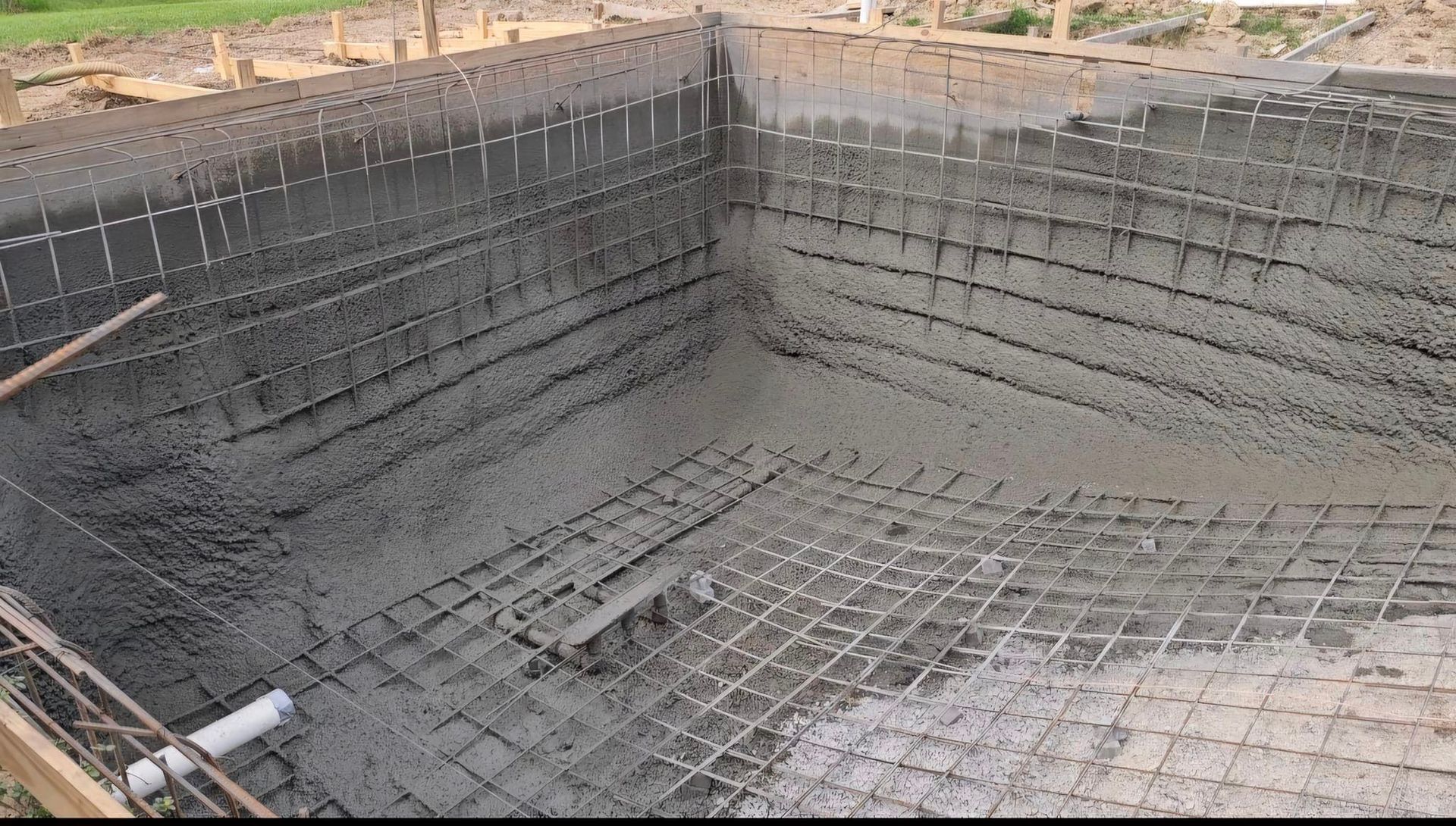 A large swimming pool is being built in a backyard.
