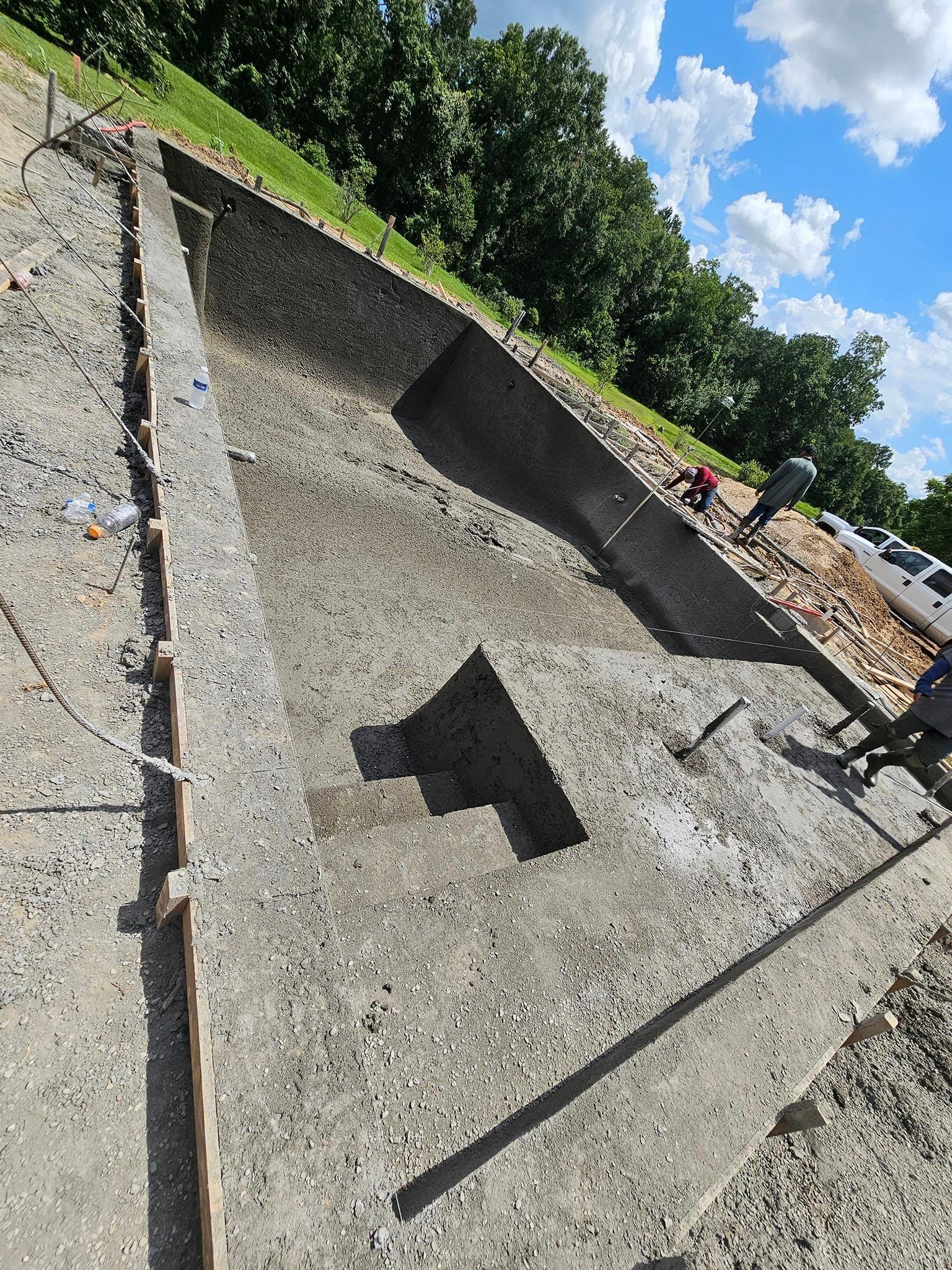 A large concrete pool is being built in a field.