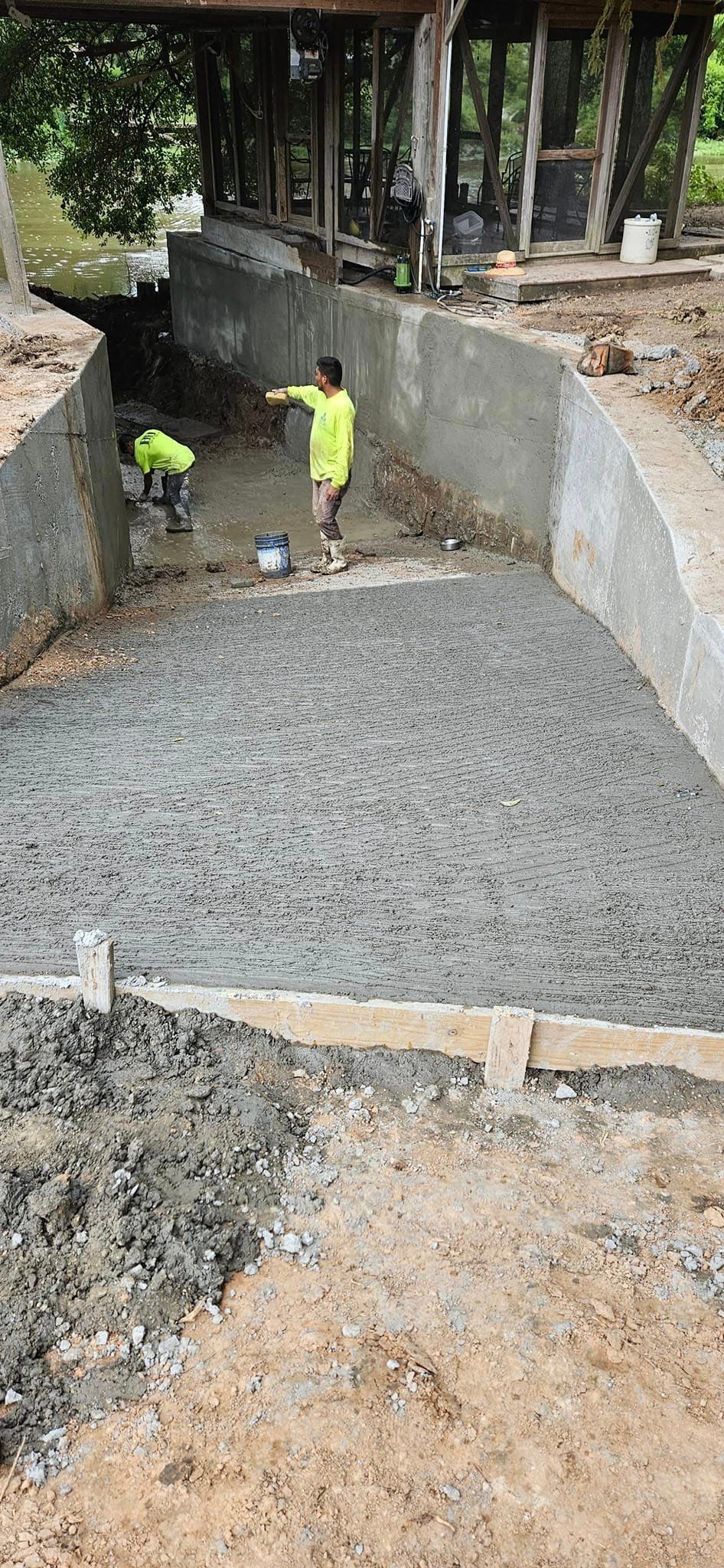 A man is pouring concrete into a pool.