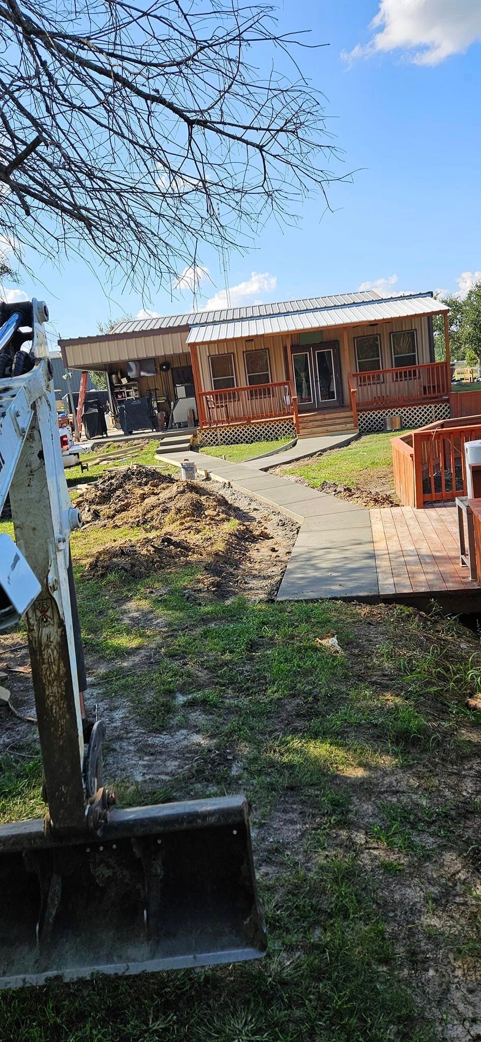 A bulldozer is digging a hole in the grass in front of a house.