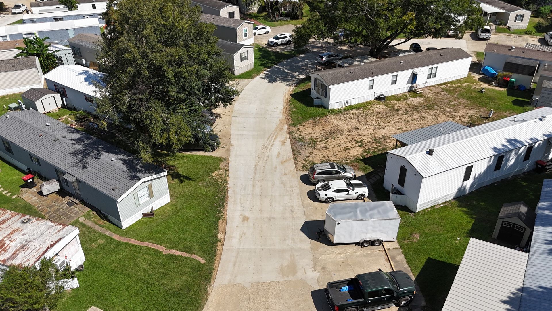 An aerial view of a mobile home park with lots of houses and trucks parked on the side of the road.