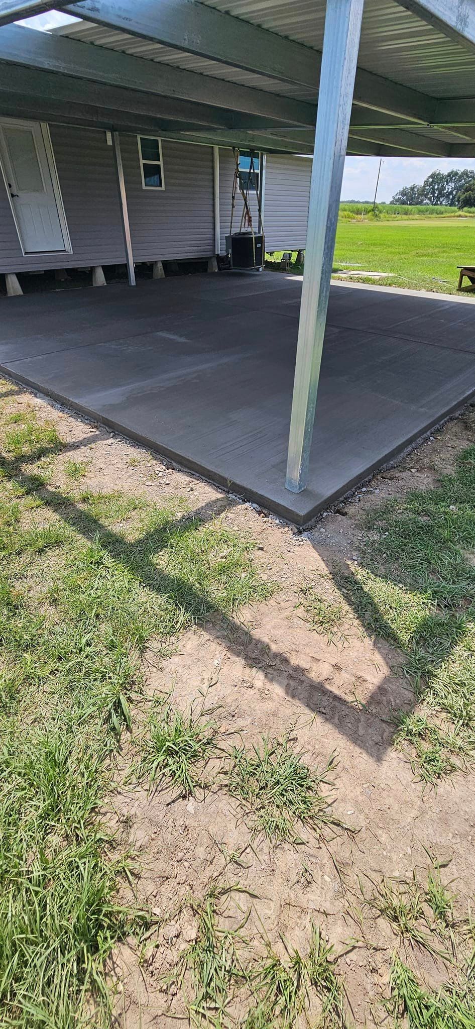 A concrete driveway under a covered patio next to a house.