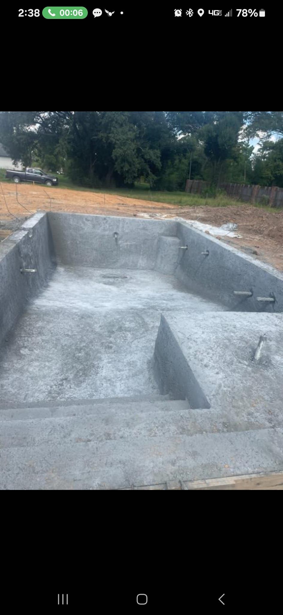 A large concrete pool is being built in a dirt field.