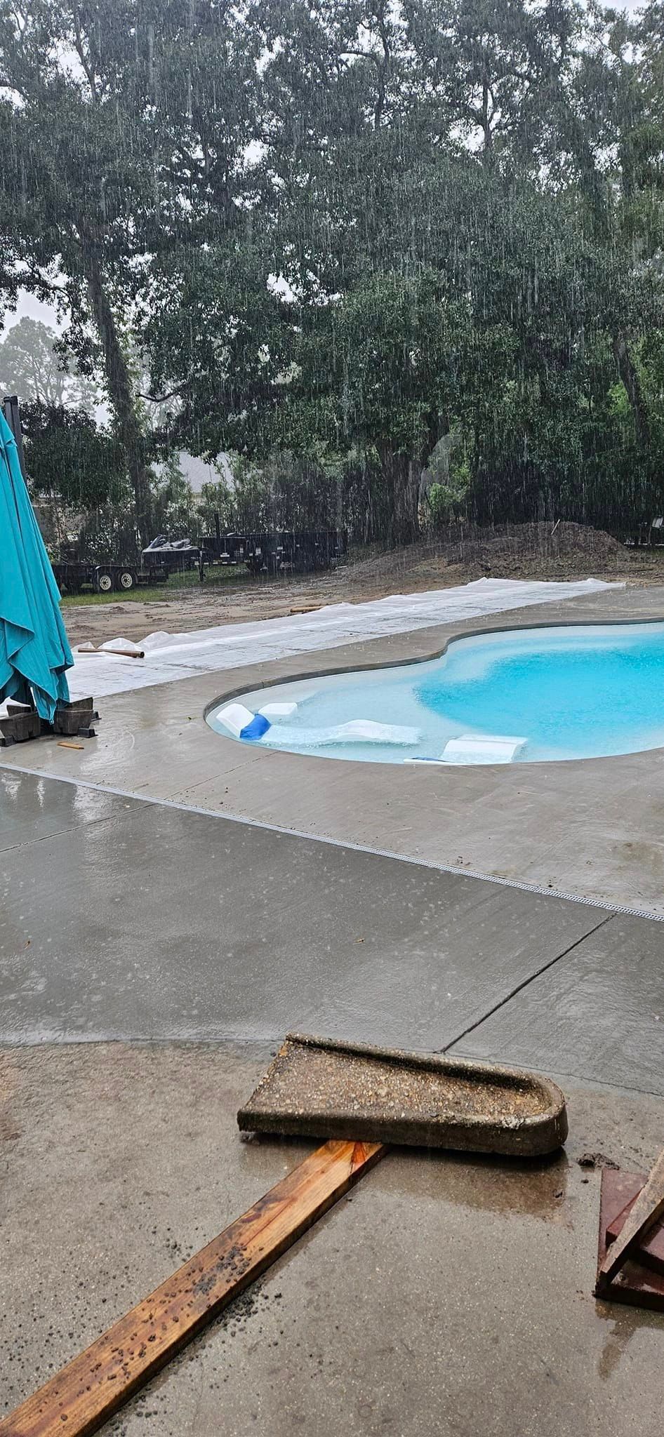 A hammer is laying on the ground in front of a swimming pool.
