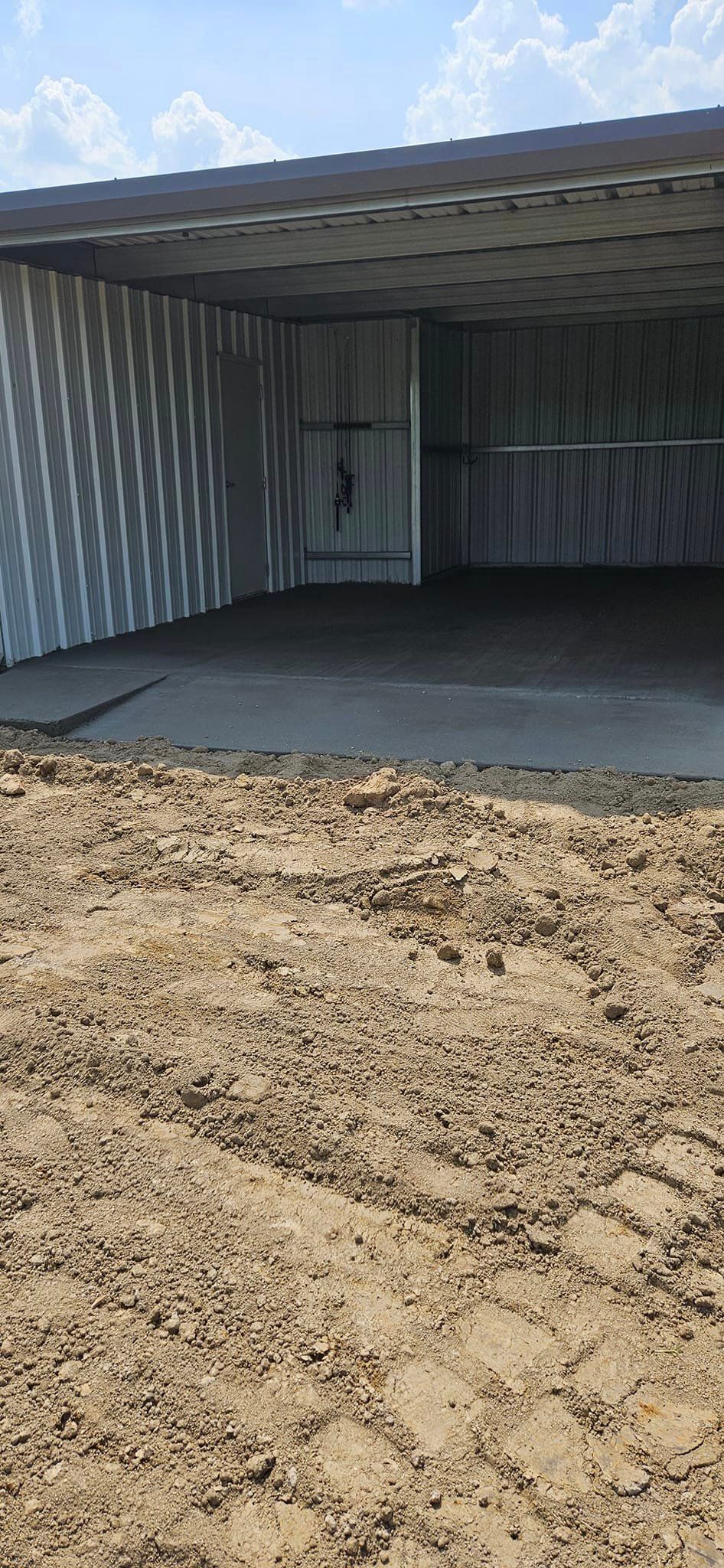 A shed is sitting in the middle of a dirt field.