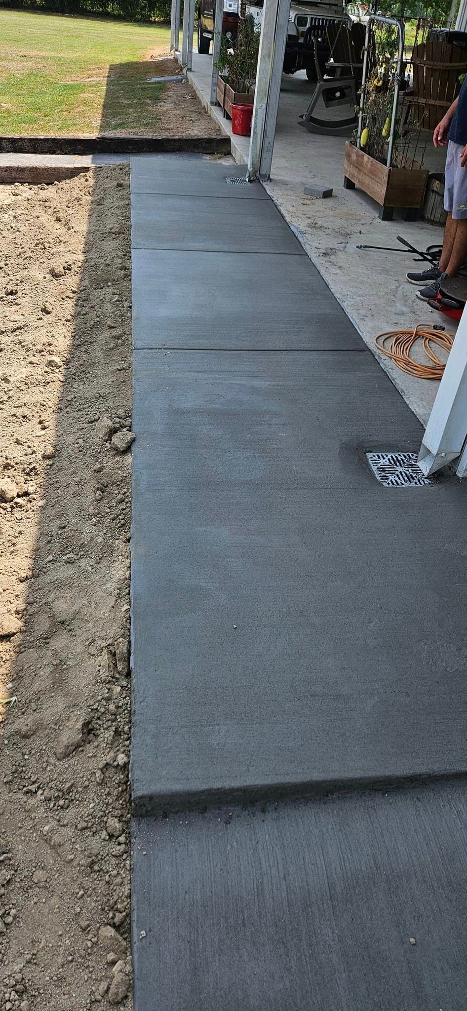 A person is sitting on a porch next to a concrete walkway.