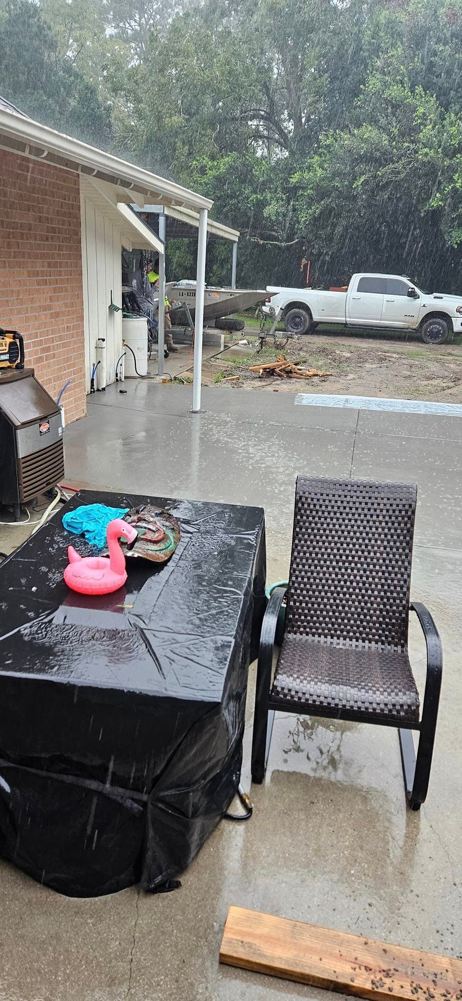 A patio with a table and chairs in the rain.