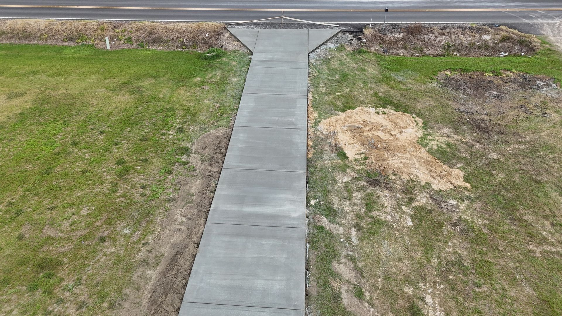 An aerial view of a concrete walkway leading to a road.
