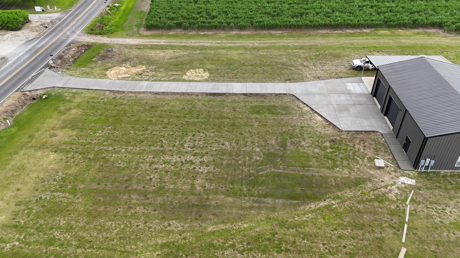 An aerial view of a building in the middle of a field next to a road.