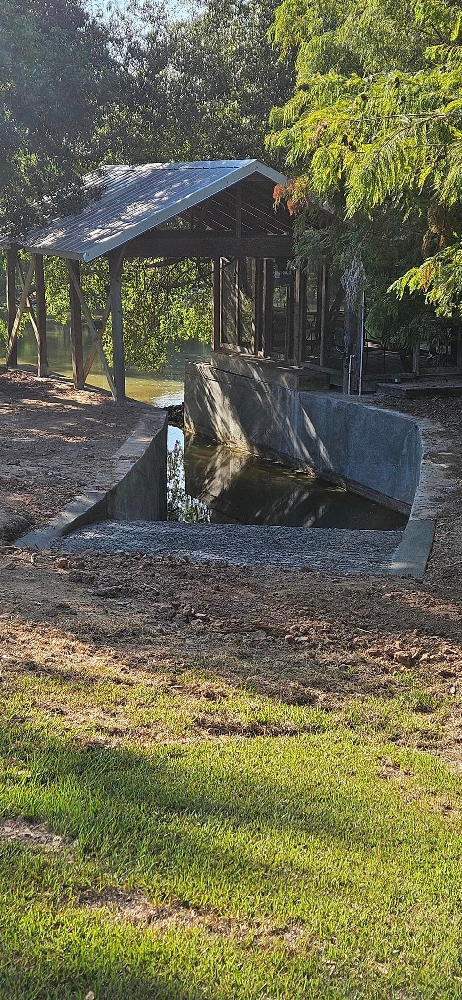 A large rock in the middle of a grassy field with trees in the background.