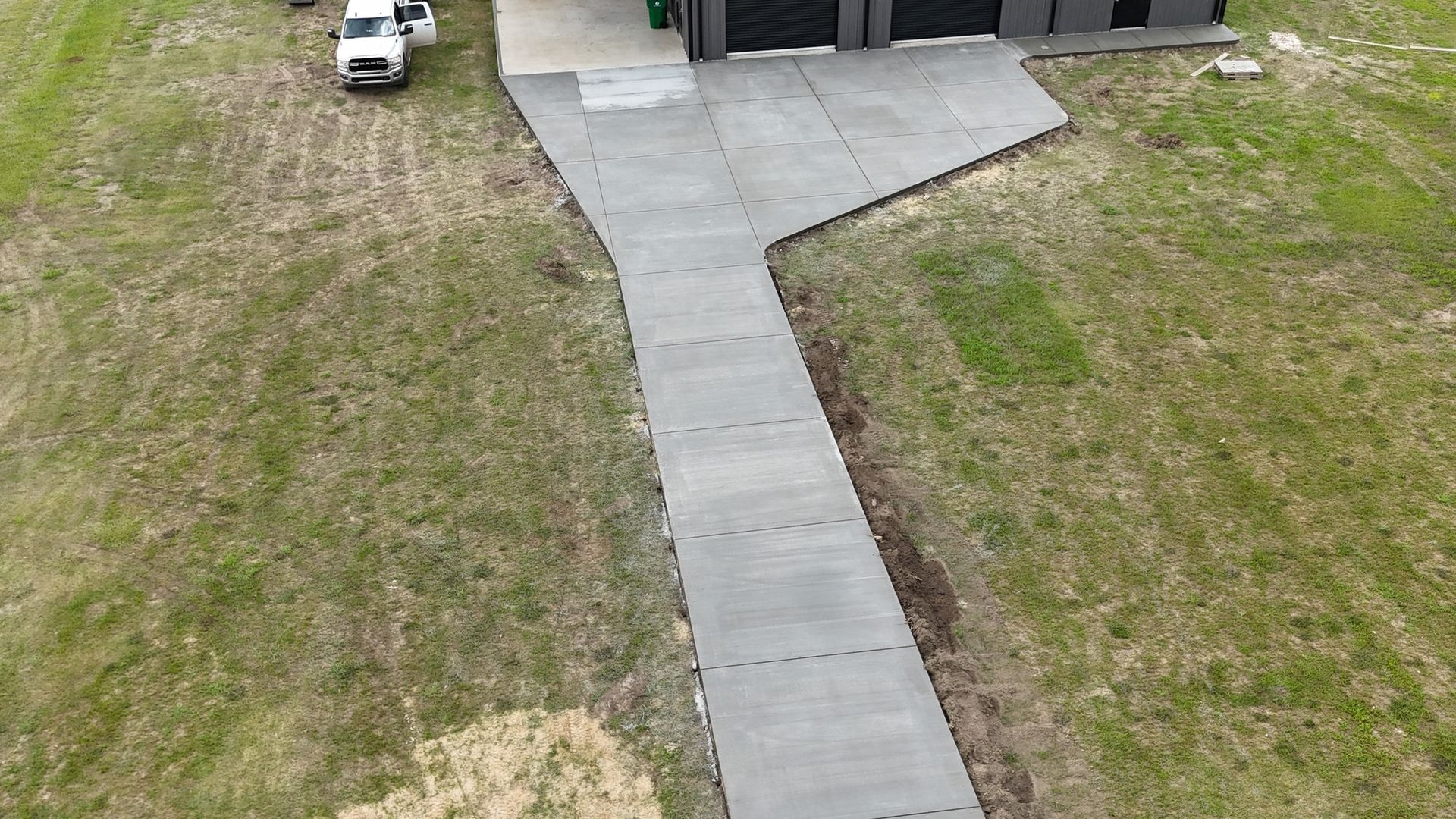 An aerial view of a concrete driveway leading to a house.