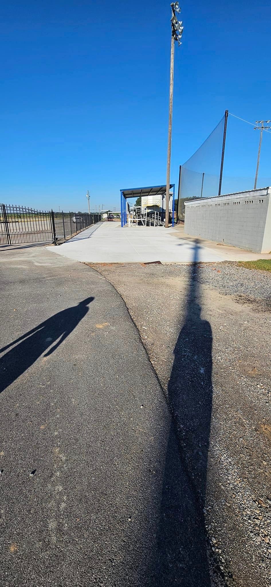 A person 's shadow is cast on a gravel road.