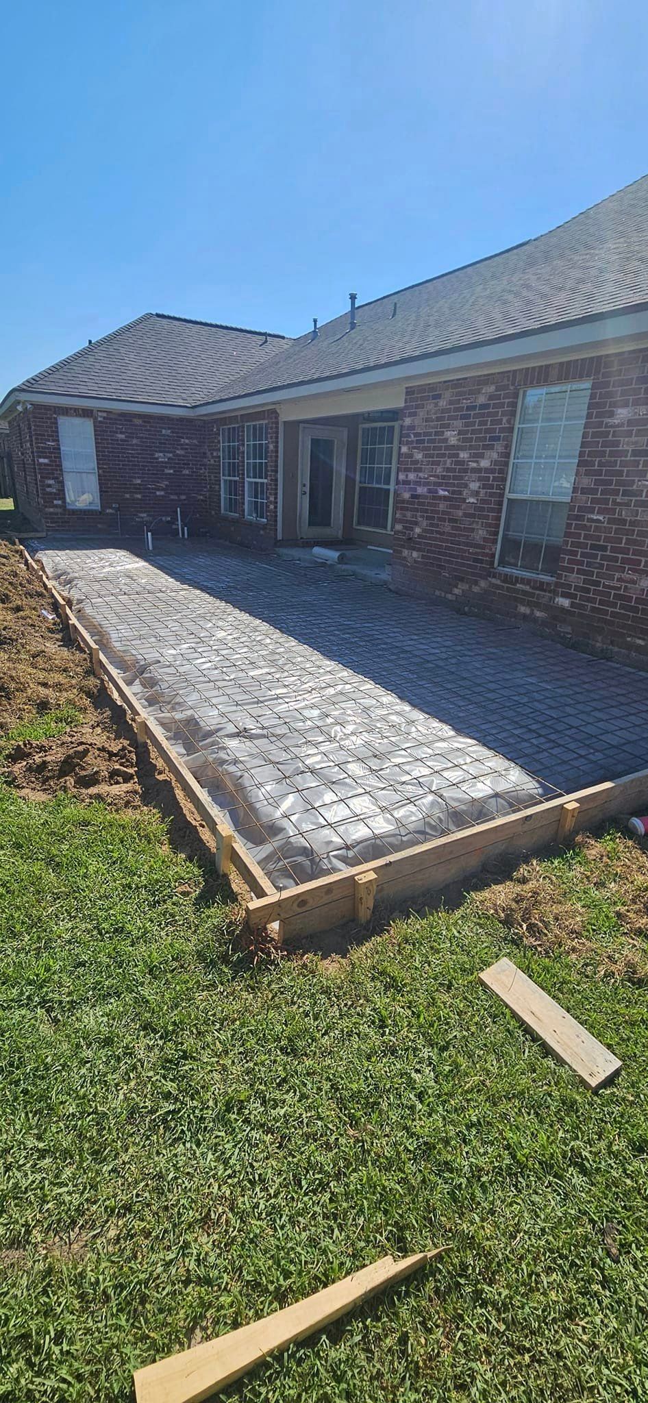 A brick house with a concrete walkway being built in front of it.