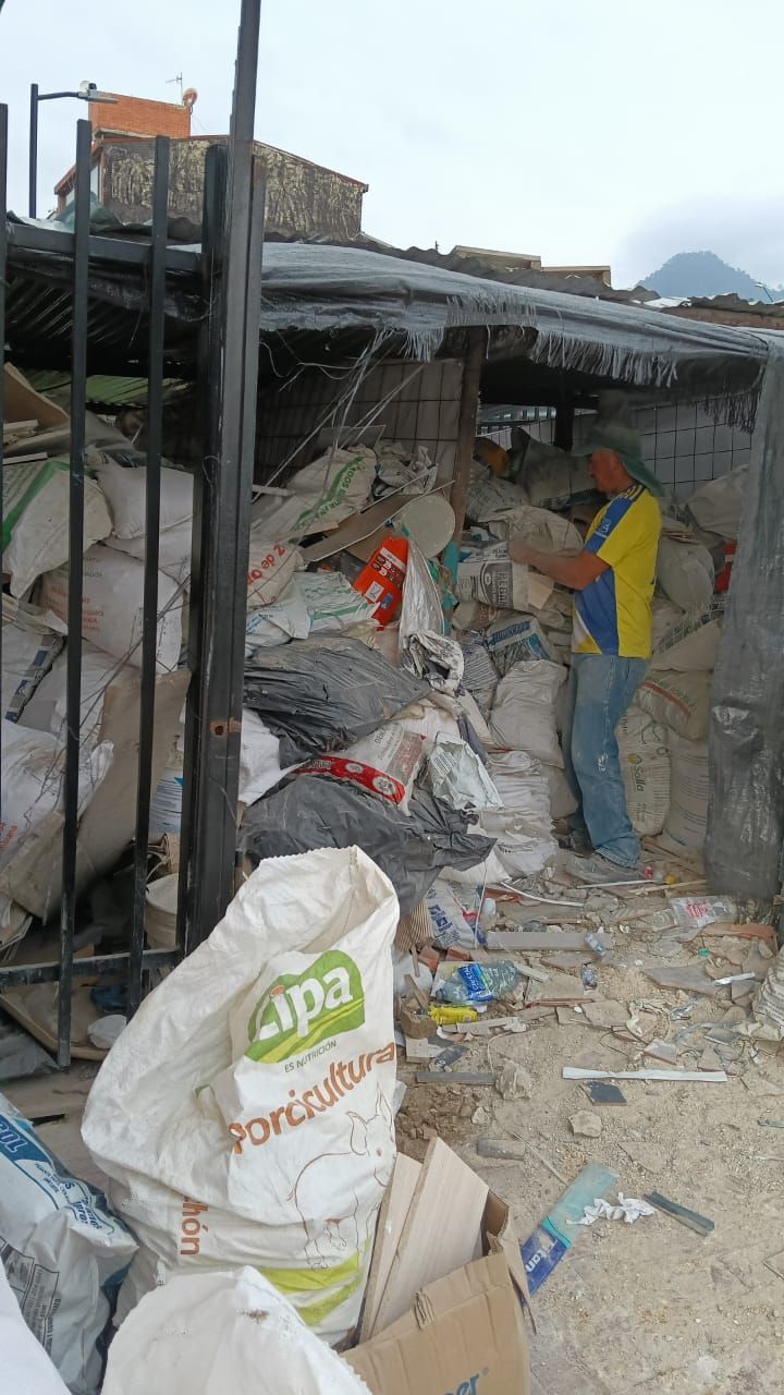 Un hombre está parado frente a una pila de bolsas de basura.