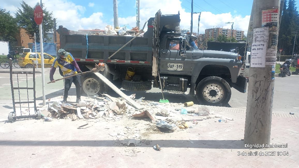 Un hombre está parado al lado de un camión de volteo al costado de la carretera.