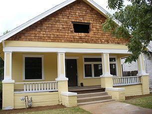 Yellow house with brown shingle siding, white trim, and a small porch.