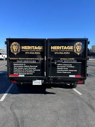 A black dump truck with a lion on the back is parked in a parking lot.