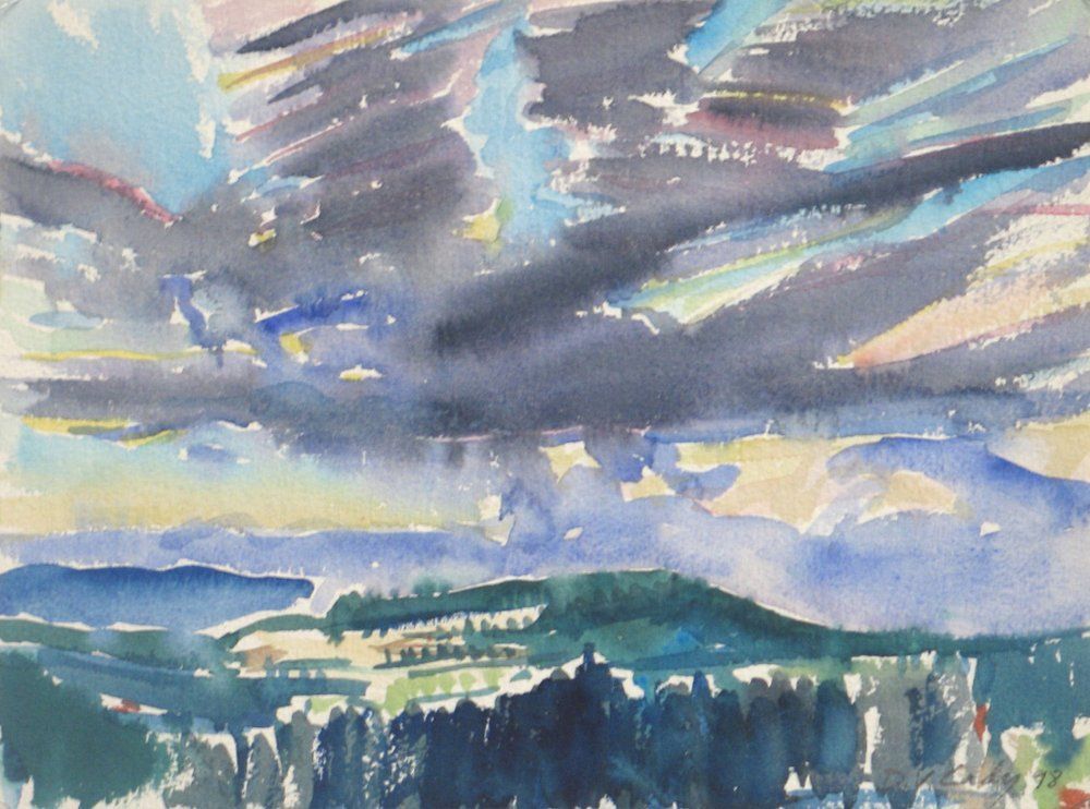 Dark storm clouds above rolling green hills and trees under a light sky