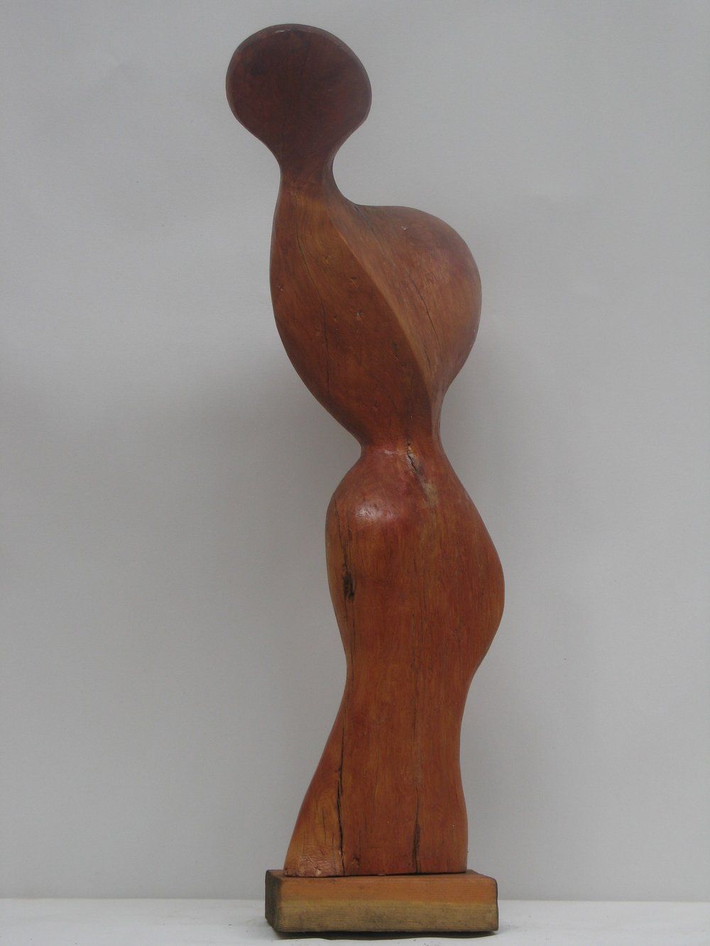 Wooden abstract sculpture of a standing figure with a rounded head and curved body