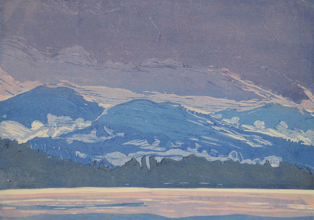 Mountains in shades of blue and white under a purple-gray sky
