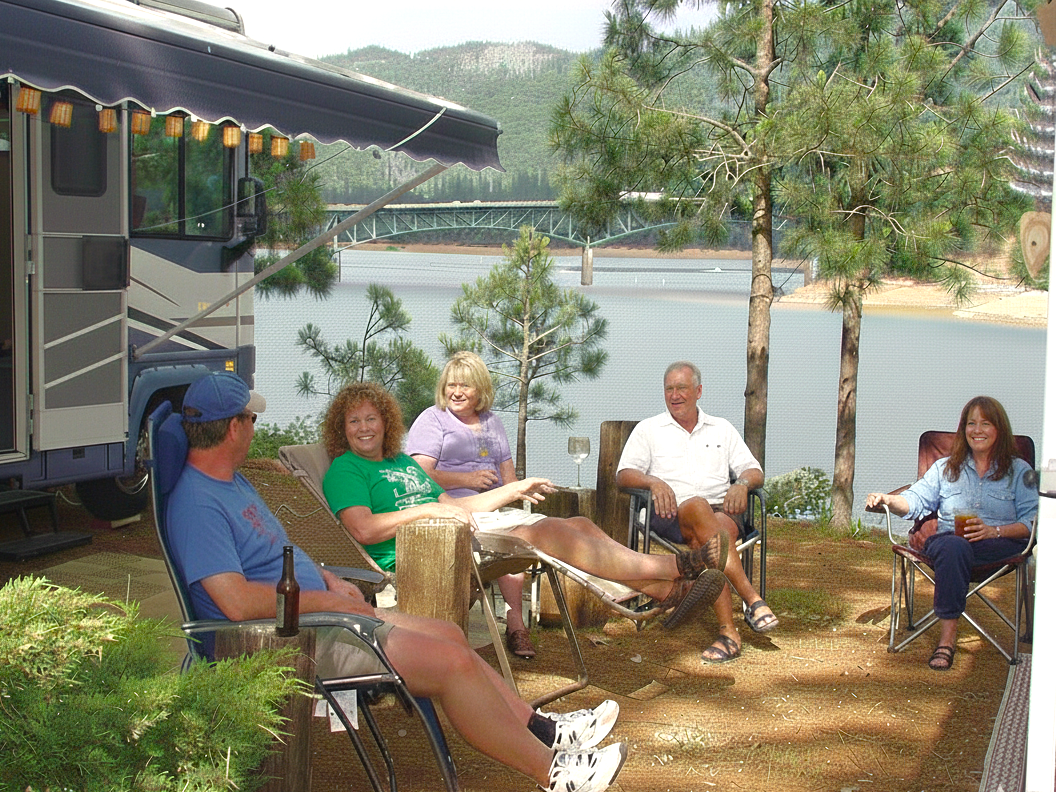 A group of people are sitting on a porch looking at the sunset.