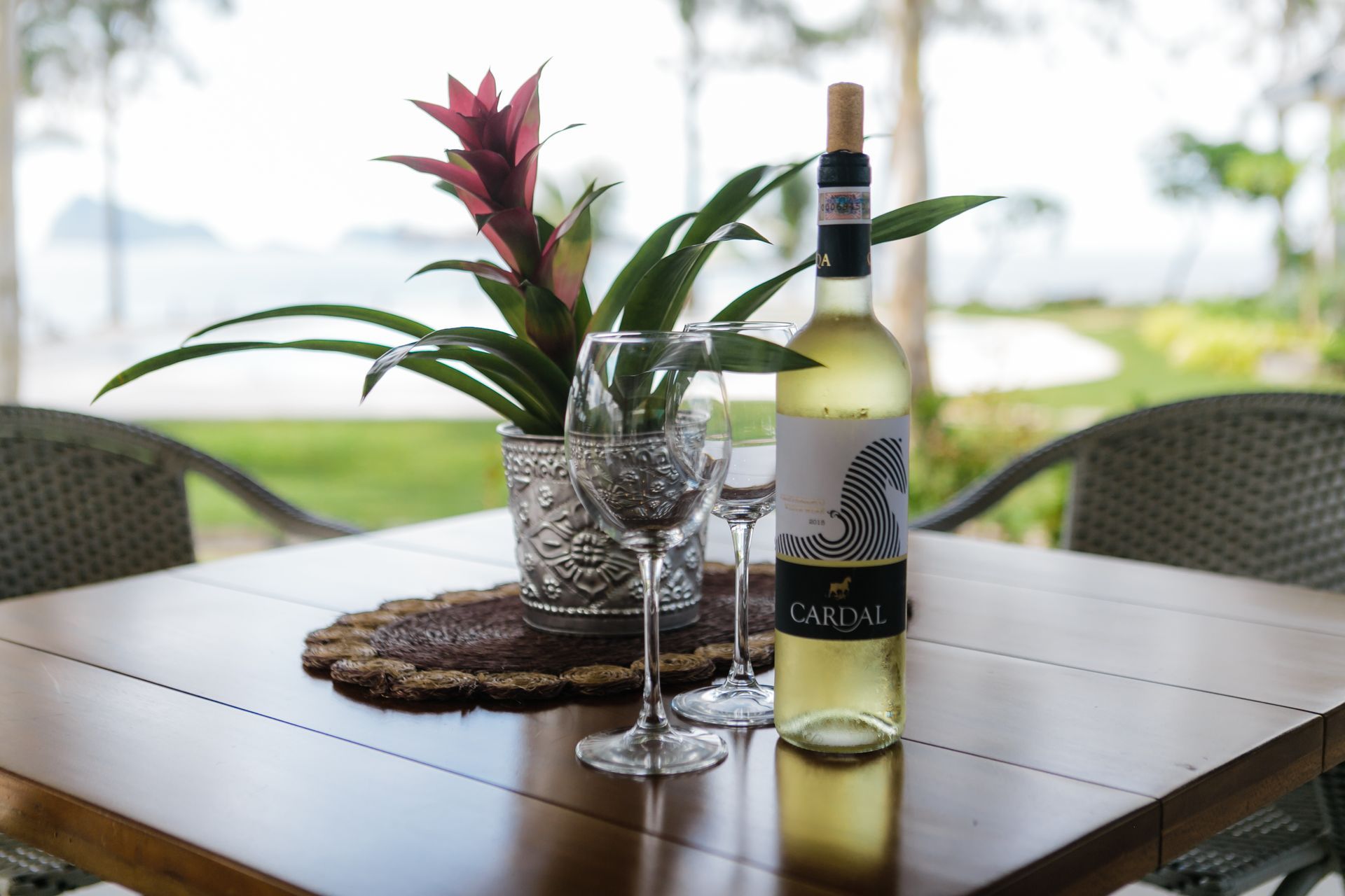 A bottle of wine sits on a wooden table next to two wine glasses.