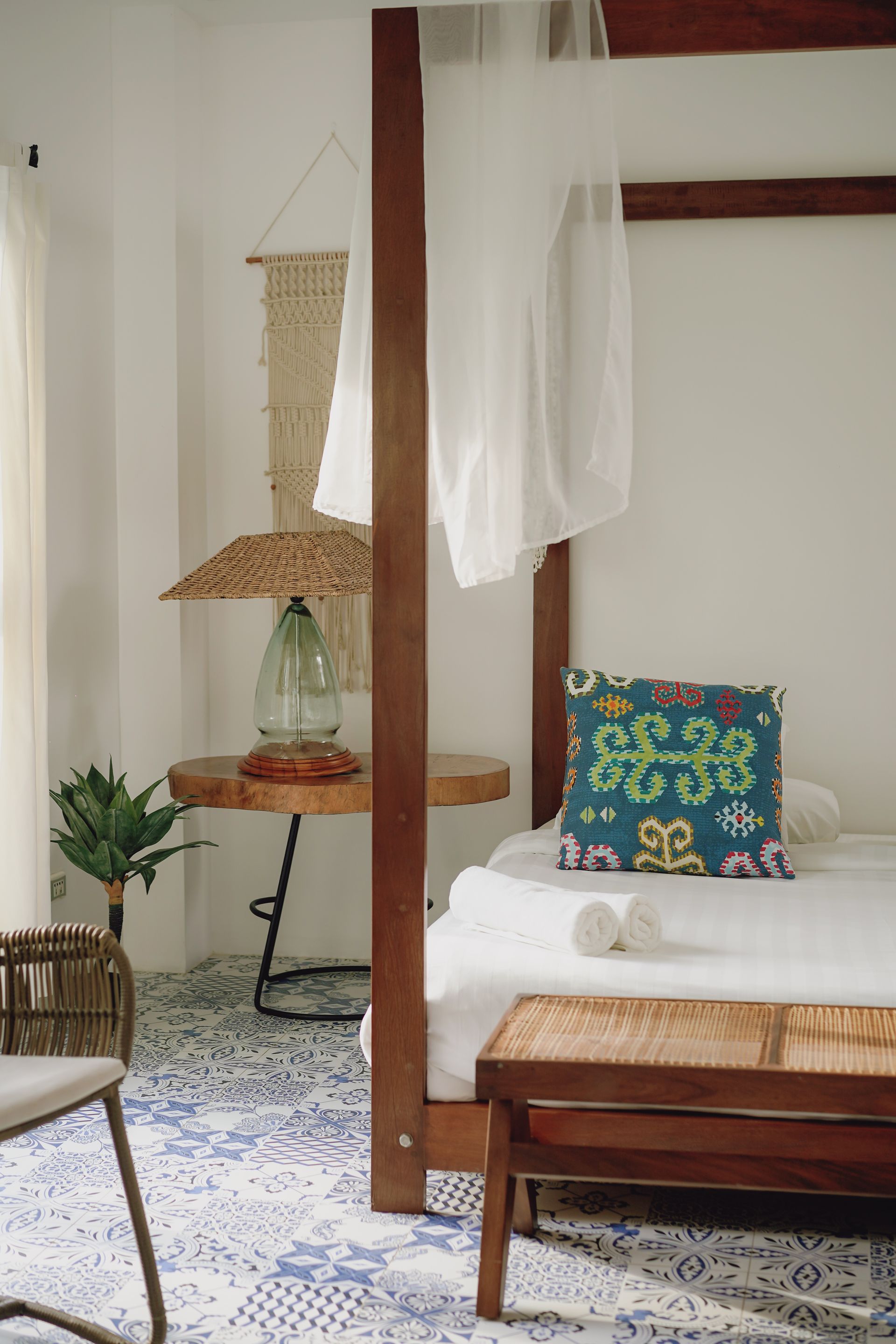 A bedroom with a four poster bed and a bench.