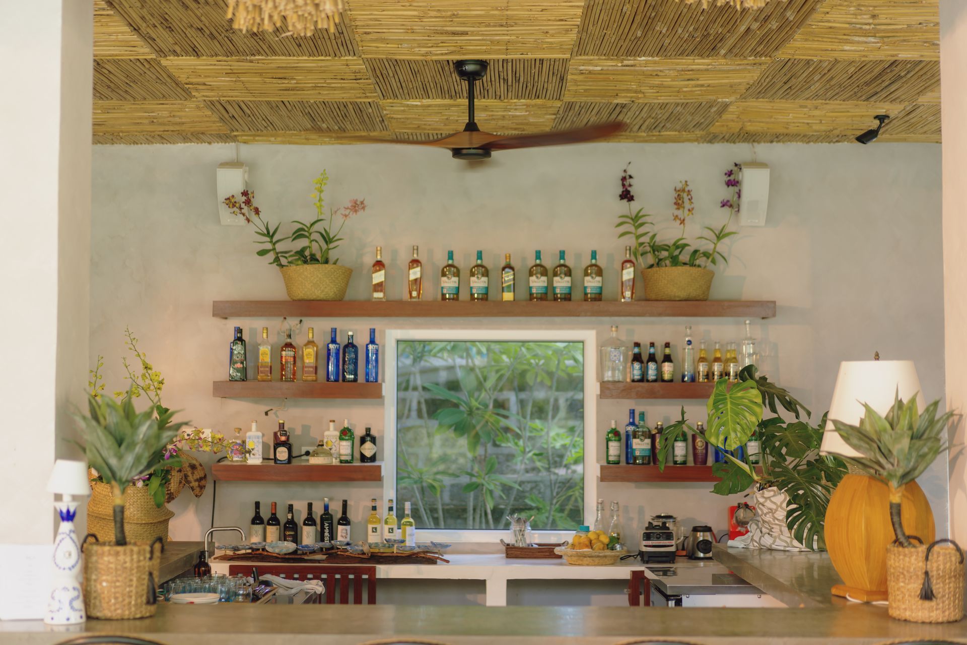 A kitchen with lots of bottles on shelves and a ceiling fan.