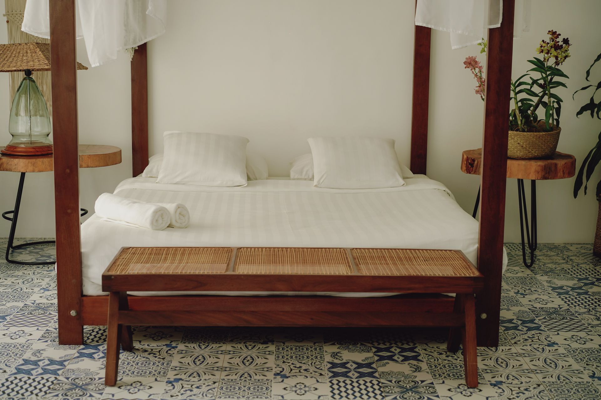 A four poster bed with a bench underneath it in a bedroom.