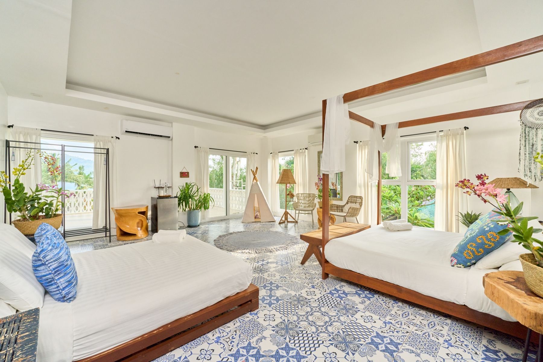 There are two beds in the room with a blue and white tile floor.