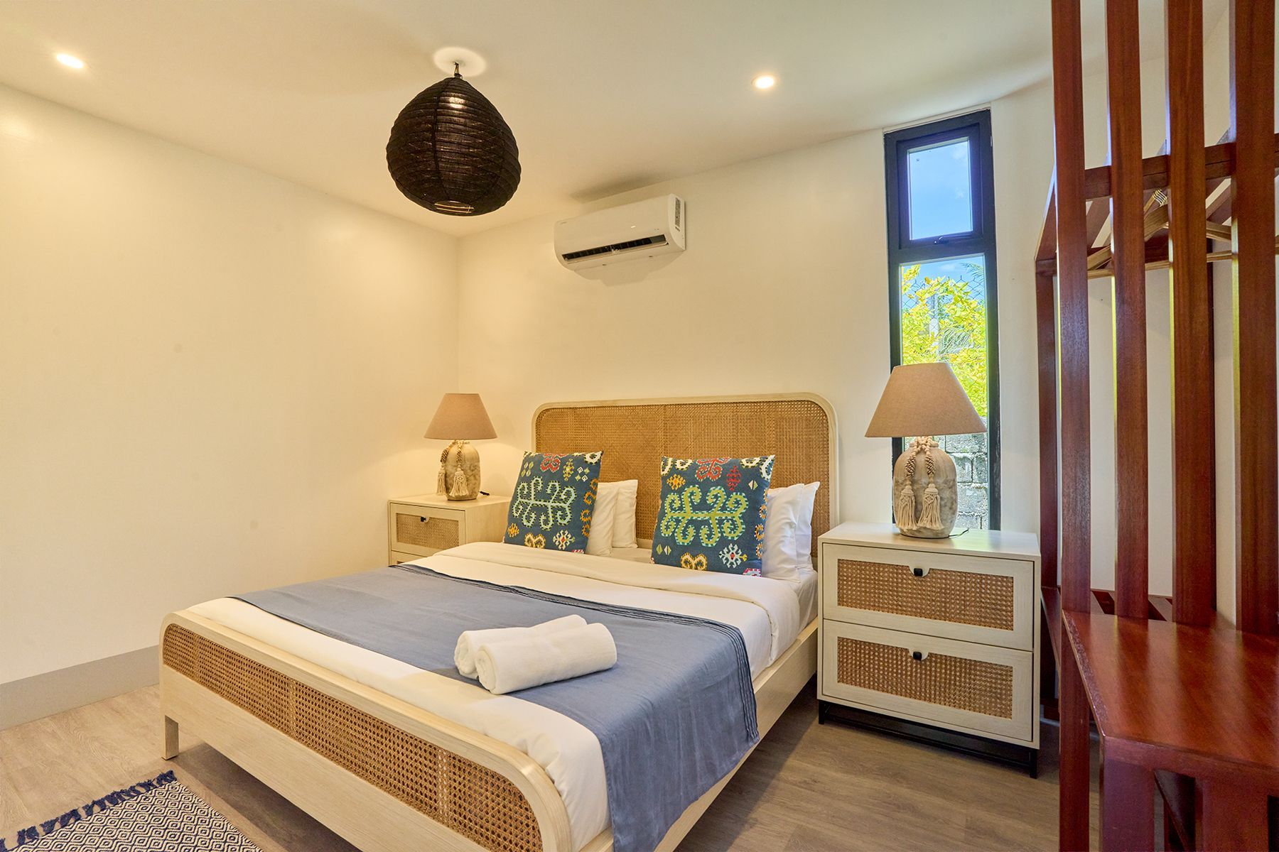 A bedroom with a bed , nightstand , lamps and a window.